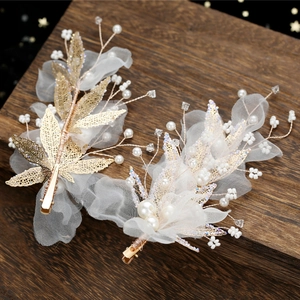 Détail de pinces à cheveux de mariée avec feuilles dorées, perles et fleurs en tulle blanc