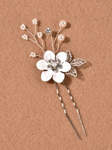 Détail d'épingle à cheveux en U argentée avec fleur en tissu blanc, perles et strass