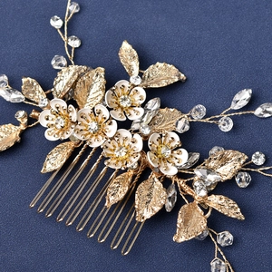 Macro shot of gold wedding hair comb with white enamel flowers and crystal leaf details