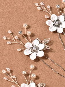 Détail d'une épingle à cheveux en U avec perles et fleurs en tissu pour coiffure de mariée