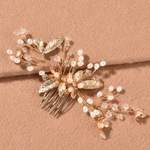 Détail d'un peigne à cheveux de mariée doré avec perles blanches et feuilles en cristal