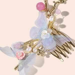 Detalle de peineta dorada con mariposas de malla azul y pequeñas flores rosas elegantes