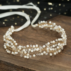 Elegant bridal headband with gold wire, pearls, and crystals on a rustic wood background
