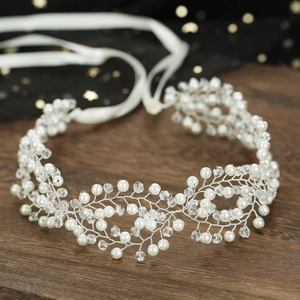 Elegant silver bridal headband featuring crystal beads and white pearls on dark wood