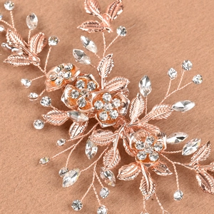 Makroaufnahme von roségoldenem Brauthaarschmuck mit Strassblumen und Blättern
