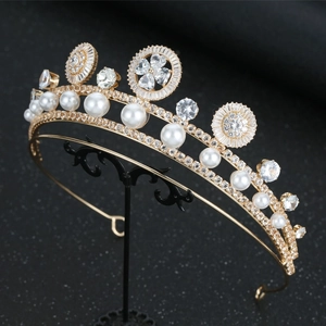 Close-up of luxury gold bridal tiara with pearls and crystals on a black stand