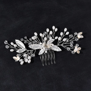 Détail d'un peigne à cheveux argenté pour mariée avec perles, cristaux et fleurs câblées
