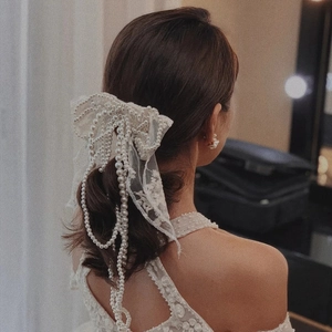 Gros plan sur un noud en dentelle blanche de mariée avec élégants glands en perles de luxe