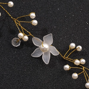 Detail of gold wire floral headband with white pearls and frosted petals on black background