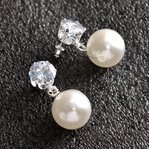 Detail van elegante bruids oorbellen met glanzende zirkoon en grote witte ronde parels