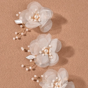 Détail de pinces à cheveux fleurs en gaze blanche avec perles et fils dorés fins