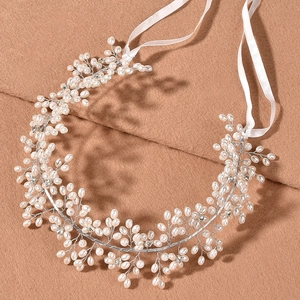 Elegant bridal pearl and rhinestone headband with white satin ribbons on camel wool background