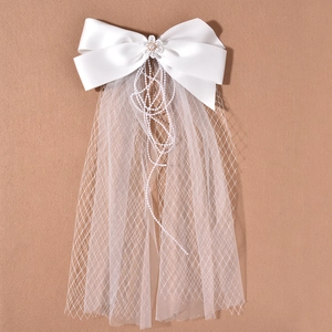 Elegant bridal hair bow with pearls and white floral accents on soft tulle bridal veil