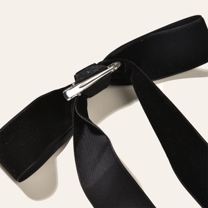 Detail view of the secure silver metal clip attached to black velvet bow hair accessory