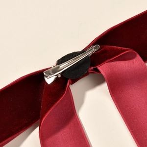 Detail of burgundy velvet bow hair clip showing smooth satin lining and metal alligator clip