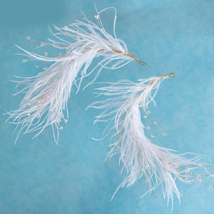 Elegant bridal feather hair clips with gold wire and crystals on light blue background