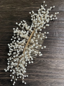 Détail macro du peigne à cheveux de mariée avec perles blanches et fils dorés tissés