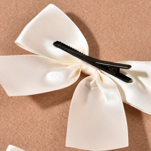 Detailed macro view of the cream satin ribbon texture on these bridal wedding hair bows