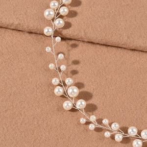 Dettaglio di acconciatura da sposa con perle bianche e filo d'argento intrecciato
