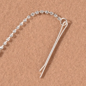 Macro shot of a silver rhinestone tassel hair clip on a soft textured fabric background