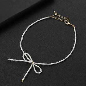 Détail du collier de perles blanches avec pendentif nœud tissé et fermoir doré réglable