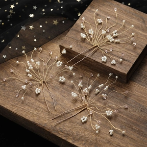 Close-up of bridal U-shaped hair pins with pink crystals and pearls on wood