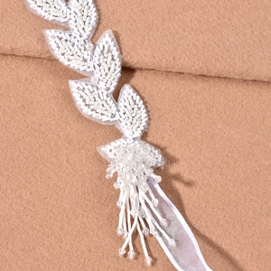 Detail of beaded bridal headpiece with white sequins and crystal leaf tassel accents