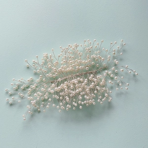 Détail du peigne à cheveux de mariée avec branches en fil d'argent et perles blanches d'ornement