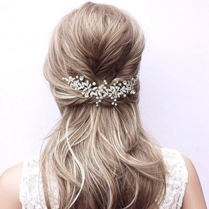 Détail d'un peigne de mariée avec fleurs argentées et perles sur cheveux blonds