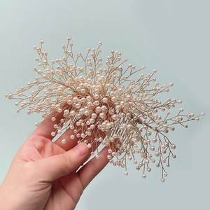 Gros plan sur un peigne de mariée fait main avec fils dorés et perles blanches