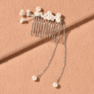 Elegant silver hair comb with white pearls and long chain tassels on warm fabric