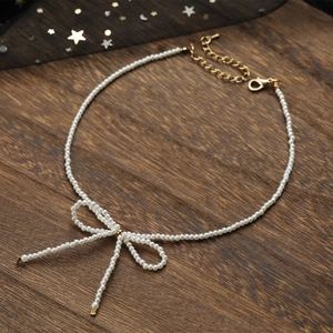 Gros plan du collier de perles en nœud avec chaîne dorée réglable sur fond de bois sombre