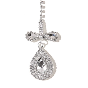 Macro detail of silver rhinestone headpiece featuring a bow and teardrop crystal pendant