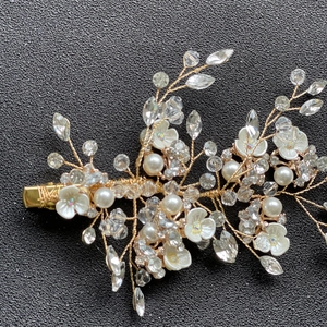 Détail d'une pince à cheveux de mariée faite main avec perles, cristaux et fils dorés