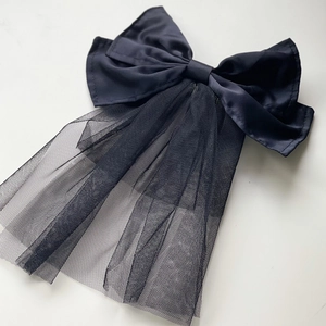 Elegant black satin bow hair clip with tulle veil detail on a clean white background
