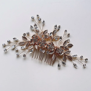 Peigne à cheveux de mariage doré avec fleurs en cristal et feuilles sur fond blanc