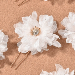 Close-up of white mesh flower hair pin with sparkling rhinestone and golden U-shaped needle