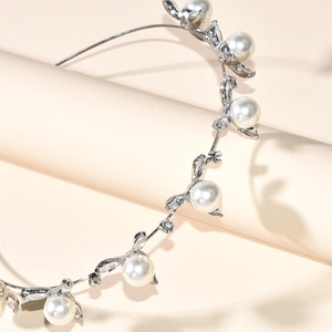 Elegant silver bridal tiara featuring white pearls and crystals on a leafy metal base