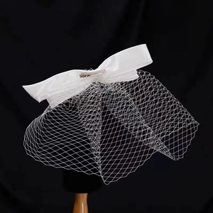 Elegant white bridal hair clip with satin bow and birdcage veil for weddings