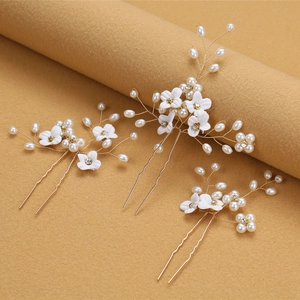 Three-piece bridal hair pins featuring white fabric flowers, pearls, and crystals in gold