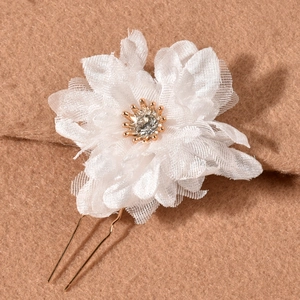 Detailed macro view of white layered tulle floral hair pin with a central sparkling rhinestone