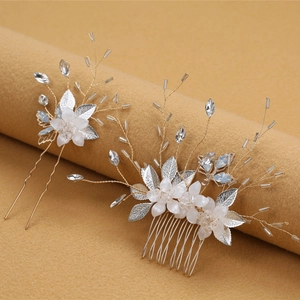 Dettaglio di accessori per capelli da sposa con fiori bianchi e foglie di perline