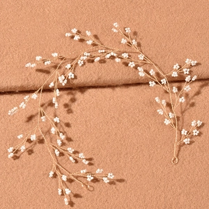 Elegant gold bridal hair vine with delicate white beads on brown textured fabric