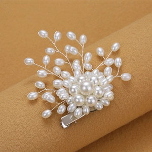 Elegant pearl hair clip with white pearls and silver wire on a brown background