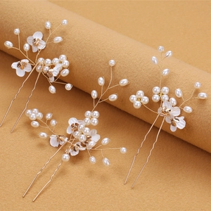 Macro detail of bridal U-shaped hair pins with white flowers and ivory faux pearls