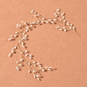 Detail of handcrafted gold wire bridal headband with white faux pearl flower clusters