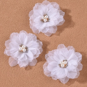 Close-up of three white organza flower hair clips with faux pearls and rhinestones