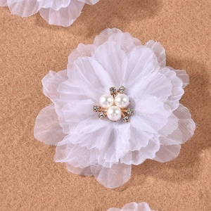Detailed close-up of white chiffon flower hair clips with pearls and small rhinestones