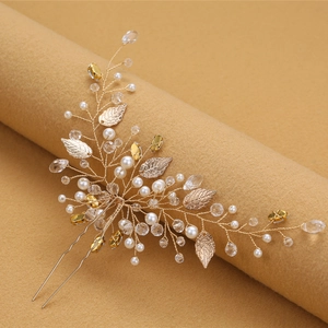 Elegant gold bridal hair pin with metal leaves, pearls, and crystals on a styling stand