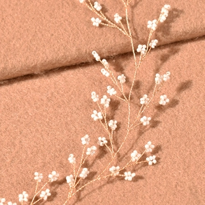 Macro view of handmade gold wire hairpiece with delicate white beads for wedding